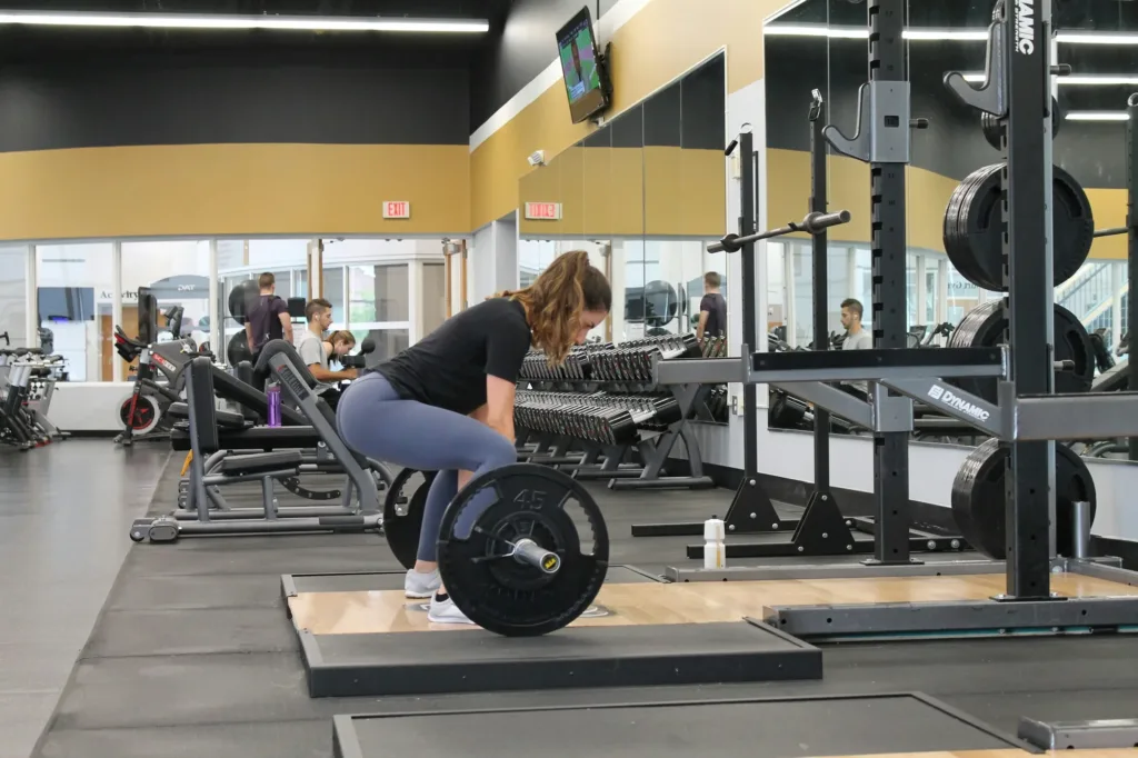 Žena izvodi mrtvo dizanje sa šipkom u teretani tijekom treninga gluteusa.