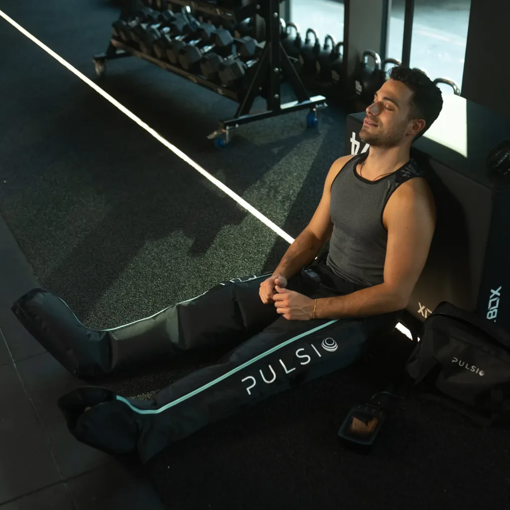 Sportaš odmara u teretani noseći Pulsio Compression čizme na nogama.